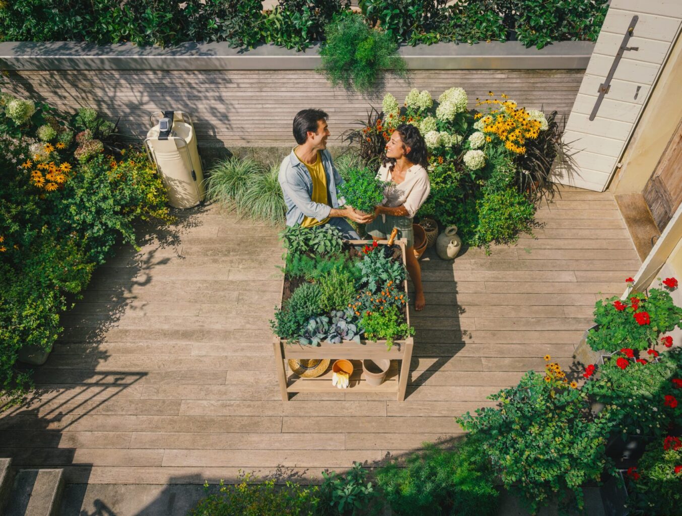 una coppia felice che sistema l'orto in terrazzo